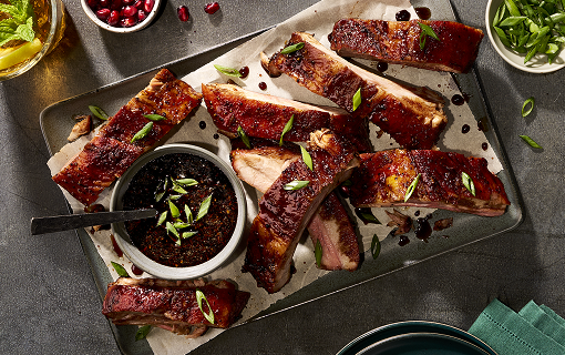 Baby back ribs cut and on a plate with a side of sauce