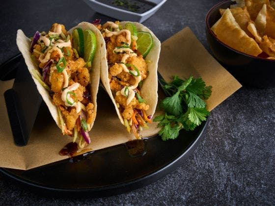 Crispy chicken bites in tortillas with Asian slaw, soy ginger sauce, and wonton chips on the side