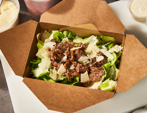 Steak Caesar Salad topped with caesar dressing, croutons, and grated cheese