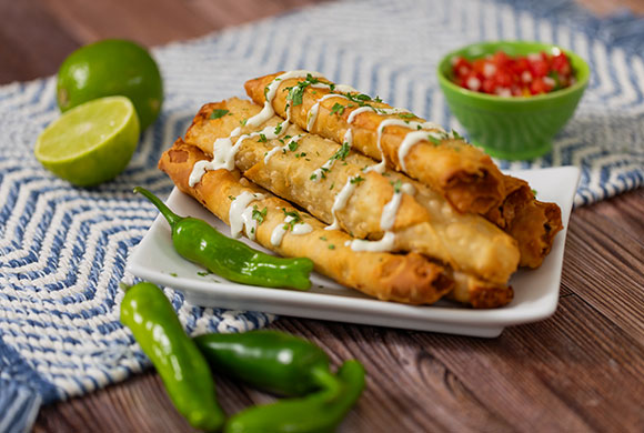 A plate of Crispitos  ® Stuffed Tortillas, perfectly complemented by sour cream and fresh herbs.